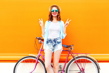 Summer happy smiling woman with bicycle on a colorful orange background