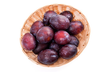Obraz premium Yellow wooden basket with ripe plums isolated on a white background..