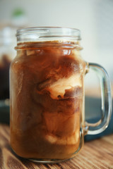 Mason jar with cold brew coffee and milk on wooden table