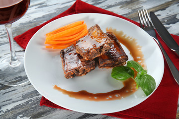 Plate with delicious ribs on wooden table