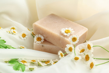 Chamomile soap with fresh flowers on fabric background