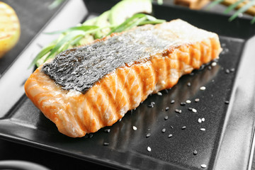 Plate with slice of delicious salmon on table, close up