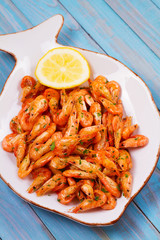 Shrimps with lemon and parsley on white plate. View from above, top studio shot