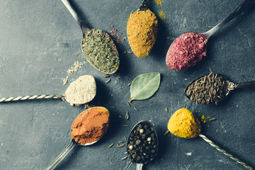 Obraz na płótnie Canvas Beautiful colored spices in a silver spoon on a dark background. The concept of cooking, healthy food