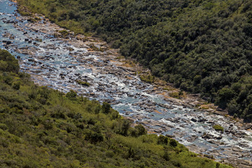 Fototapeta premium River Flowing Through Winter Vegetation Lined Valley