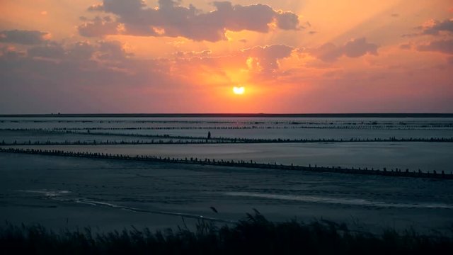Time lapse of colorful scenic sunset at Syvash lake with beautiful boiling sunlit cumulus clouds moving in orange and yellow sky. Shot in Pryozerne village, Kherson oblast, Ukraine