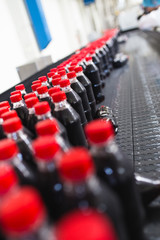 Bottling factory - Black juice or soft drink bottling line for processing and bottling juice into bottles. Selective focus. 