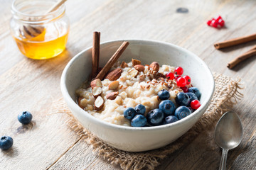 Oatmeal porridge with blueberries, almonds, cinnamon, honey, linseeds and red currants in bowl. Super food for healthy nutritious breakfast