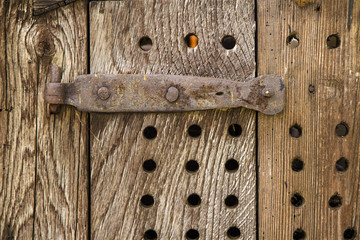 A detail from an antique wooden door with rusty metal hinge