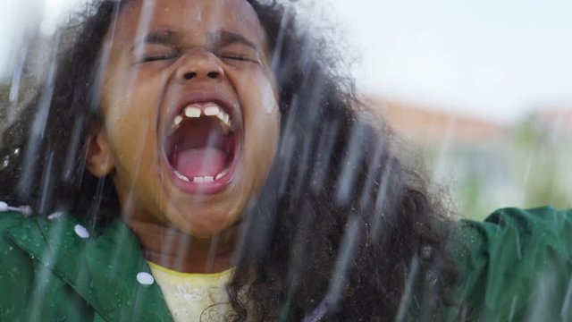 Close up of little girl with African American girl with curly hair screaming in rain