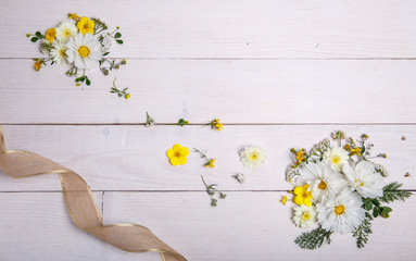 A bouquet of white flowers cosmea or cosmos with ribbon on white boards. Garden yellow flowers over handmade wooden table background. Backdrop with copy space.