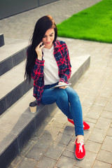 young brunette womanwith tablet serfing in internet on grass