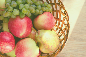 Mix of fruits in a wooden basket, lit by a ray of sun