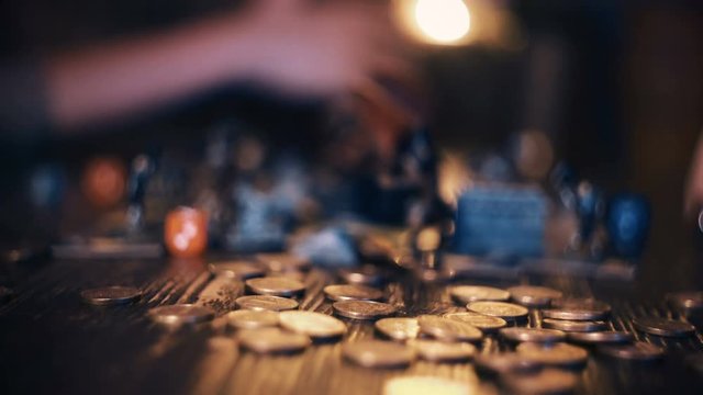 Close up of man hand dropping golden coins on dark wooden table with blurred background. Shot with Sony a7s and Atomos Ninja Flame