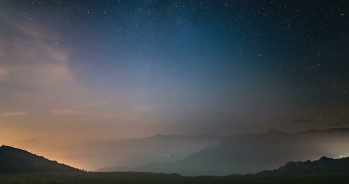 Time Lapse of the Milky way and the starry sky moving over the Italian Alps with fog and moisture resulting in a dreamlike effect. Glowing valleys below. Static version.

