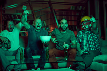 Four men watching american football game on television