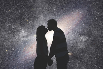 Silhouettes of a young couple under the starry sky. 