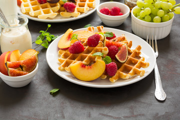 Homemade Belgian waffles with peach, raspberry, fig and honey on brown wooden background. Selective focus