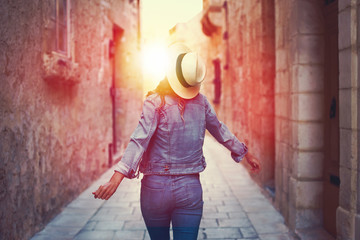 Woman in hat dancing on mediterranean narrow street