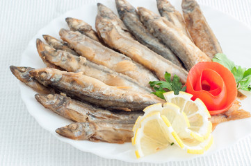 sprat anchovy fish with lemon on a white plate