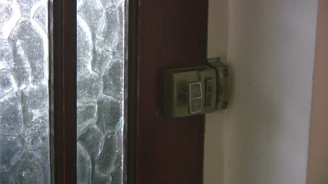 Close up interior shot of a man arriving at a house by the front door. The door is opened by a young woman to let him in. The door has frosted glass panes and a Yale type lock.