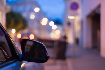 Rückspiegel eines parkenden Autos am Abend, Straße