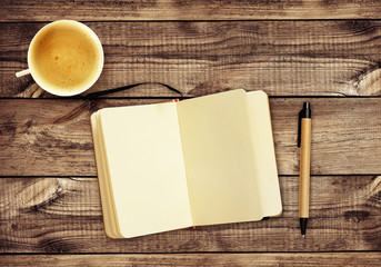 Wooden desk with notepad, pen, cup of coffee and Christmas decorations