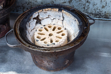 A burnt briquette and A rusted iron bowl
