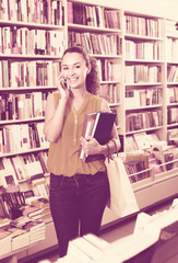 young woman with phone in book shop.