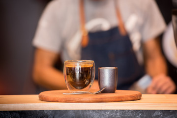 Fototapeta na wymiar Black Coffee Cup On Wooden Table And Coffee Barista ..Horizontal.Blurred Background.Film effect.