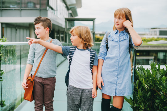 Group of 3 funny schoolkids posing outdoors, wearing backpacks. Back to school concept. Fashion for children
