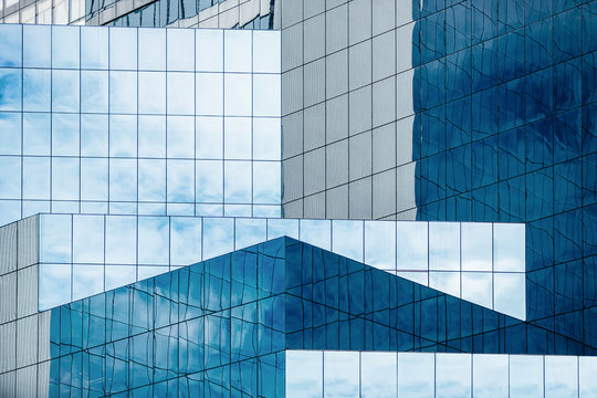 Fototapeta Blue sky and clouds reflecting in windows of modern office building
