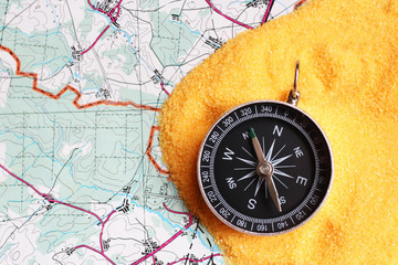 Fototapeta na wymiar compass on the sand and a map of the area