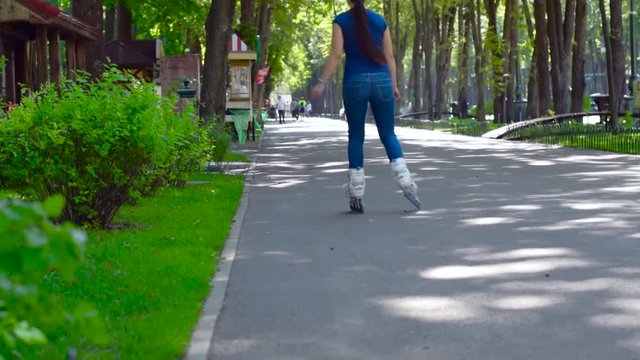 Girl rollerblading in the city park. Caucasian woman in outdoor activities.