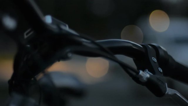 At night the steering wheel of a bicycle and a bokeh of light from the headlights of cars