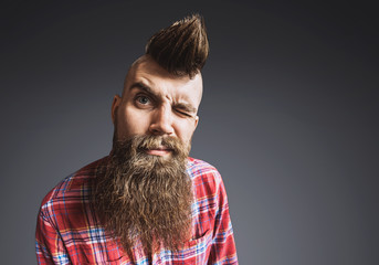 Excited trendy man portrait. Punk styled man with Mohawk hairstyle is smiling. Isolated on gray...