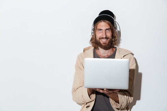 Happy hipster man using laptop computer listening music.