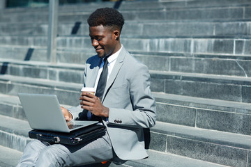 Jobless man with drink and laptop searching for vacancies in the net