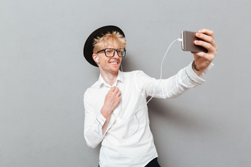 Man wearing glasses listening music while make selfie.