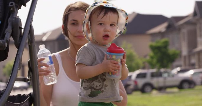 Toddler boy drinks from sippy cup with mother background