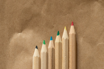 6 colored crayons in a diagonal line on beige paper background