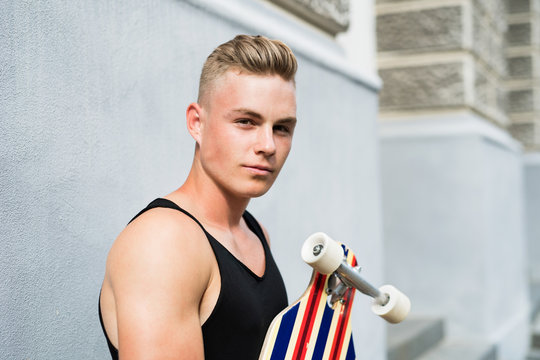 Teenage boy with scateboard in front of old building.