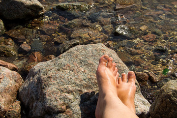 Woman's bare feet near the sea on rock