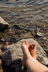 Woman's bare feet near the sea on rock