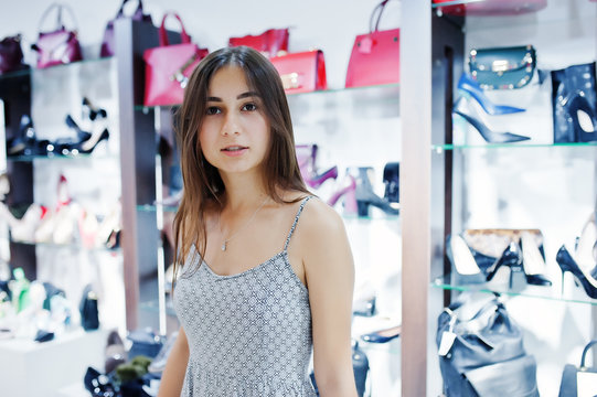 Portrait of a beautiful woman in grey dress in shoe and bag shop.