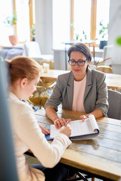 Young girl signing contract after interview with owner of cafe or restaurant