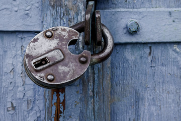 old blue wooden door locked with a padlock. Closed metal lock door security protection padlock
