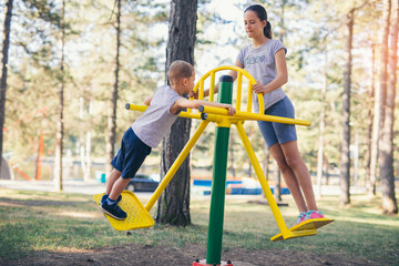 Brother and sister workout outdoors in a park with exercise machines