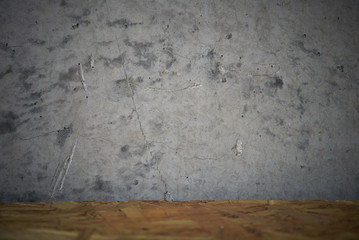 Decorative grey concrete wall and wooden table top, vignetted background. Selective focus on wall