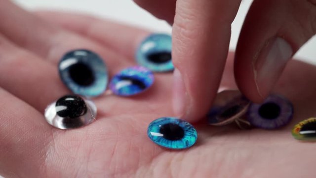 On the open palm there are many varieties of colored eyes for soft toys and handmade dolls. Accessories for needlework and creating vintage plush toys. Modern handicraft and hobby.